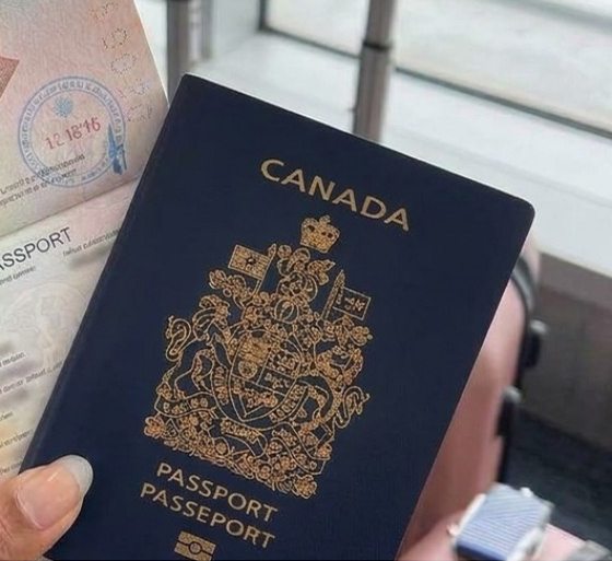 A Canadian passport held up in an airport departure hall
